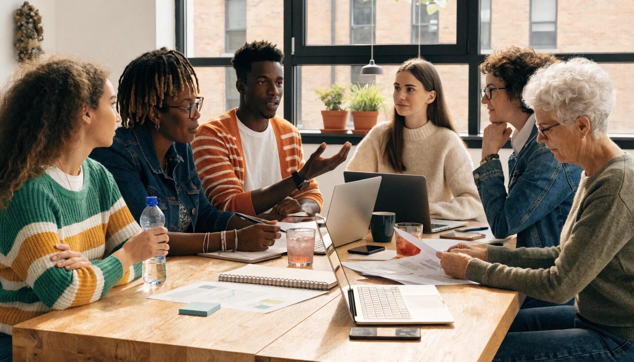 Diverse group of professionals collaborating around a laptop and health insurance documents.
