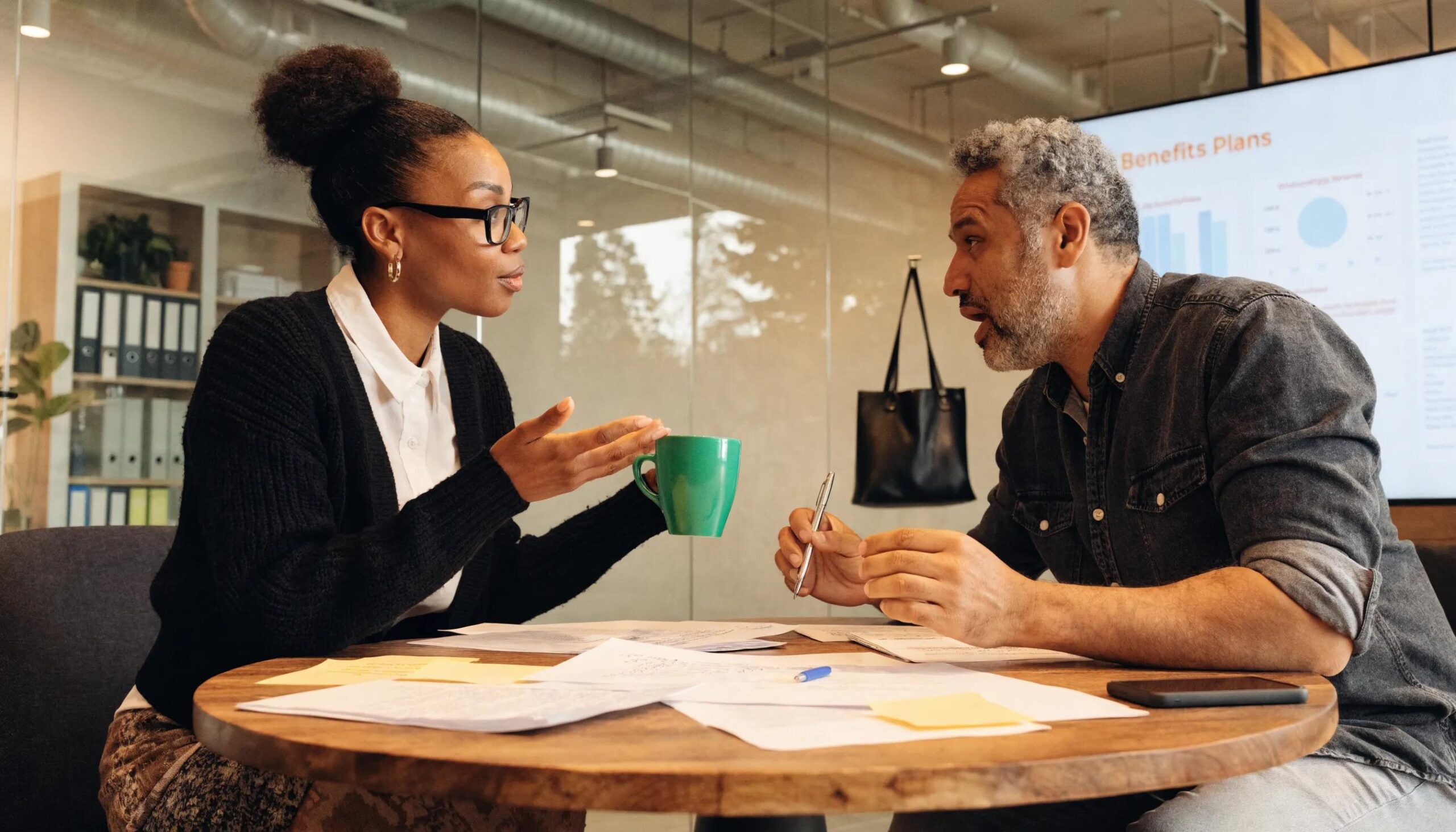 Consultant discussing employee benefits strategy with a business owner, emphasizing the importance of consulting services